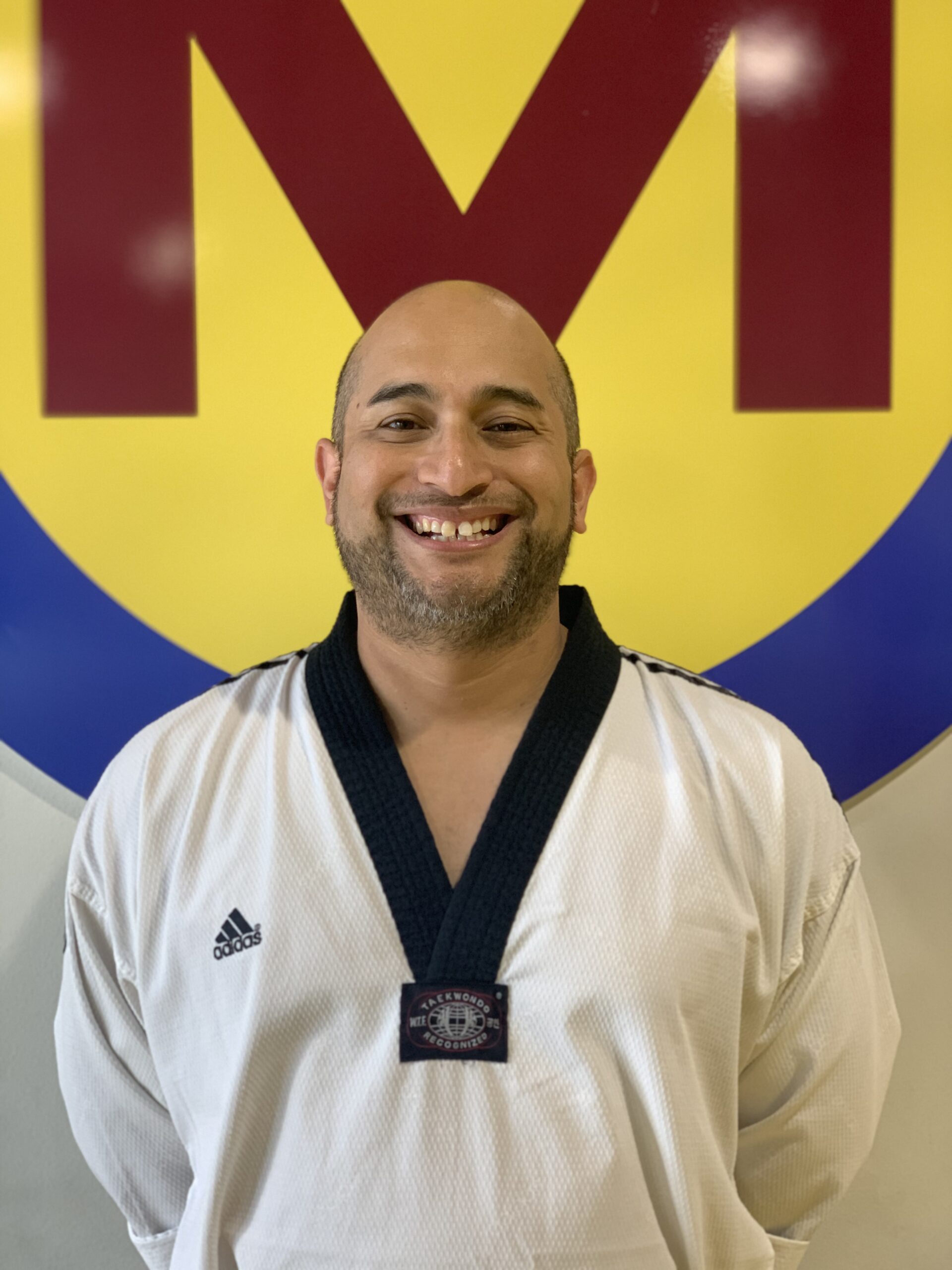 Tony Rios in a white dobok, smiling in front of the studio M